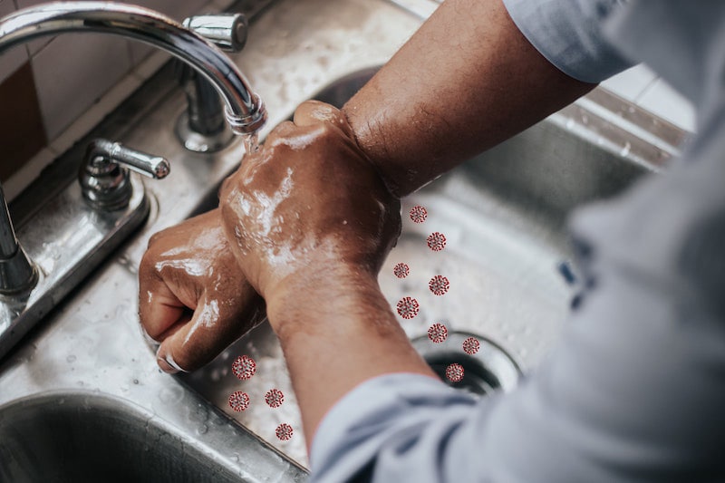 Henkilö pesee käsiään huolellisesti lavuaarissa. Koronaviruspartikkeleita valuu lavuaariin pesuveden mukana.