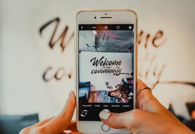 Instagram toimii self-care -kulttuurin välittäjänä. IPhonella henkilö, jonka kynnet on lakattu valkoisiksi ottaa kuvaa huoneesta, jonka seinällä lukee "Welcome to the community". Kuva piirtyy puhelimen näytölle.