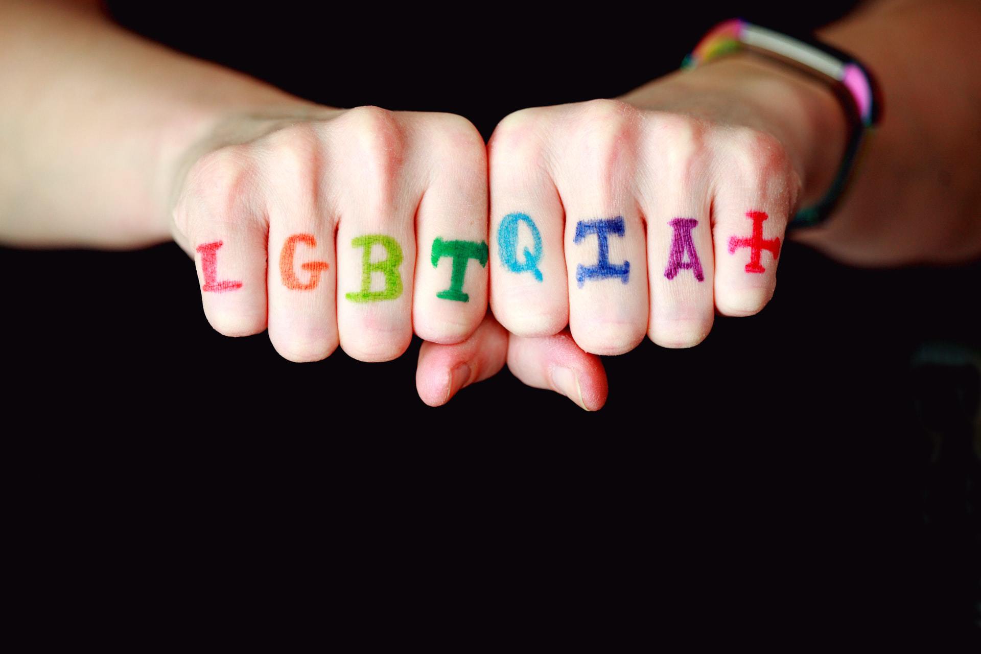 Nyrkissä olevat kädet, joiden sormiin on maalattu sateenkaaren väreillä LGBTQIA+. Panseksuaalisuus sisältyy tähän määrittelyyn.