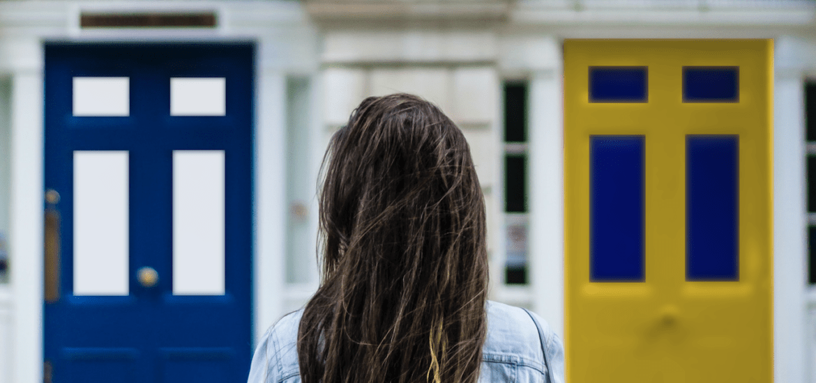 Suomenruotsalaisuus on tasapainoilua kahden identiteetin välissä. Henkilö seisoo kahden oven edessä, joista toinen on sinivalkoinen ja toinen keltasininen.