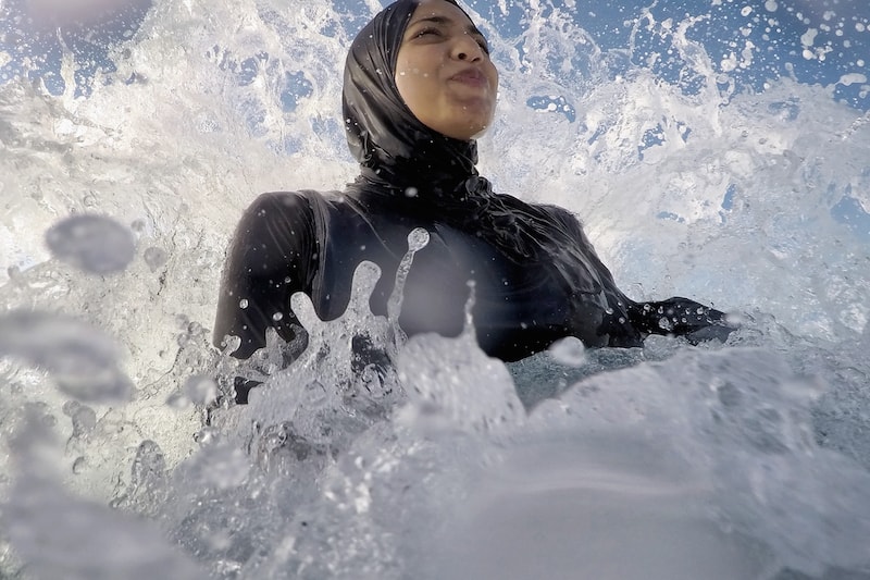 Burkini-asuinen musliminainen ui aallokossa.