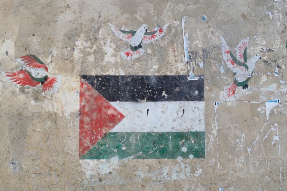 Kulunut seinämaalaus, jossa on Palestiinan lippu ja sen yläpuolella kolme rauhankyyhkyä.