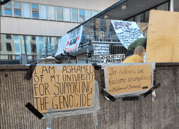 Hand written signs in front of Porthania building: I am ashamed of my university supporting the genocide. In silence we become accomplices, Mahmoud Darwish.