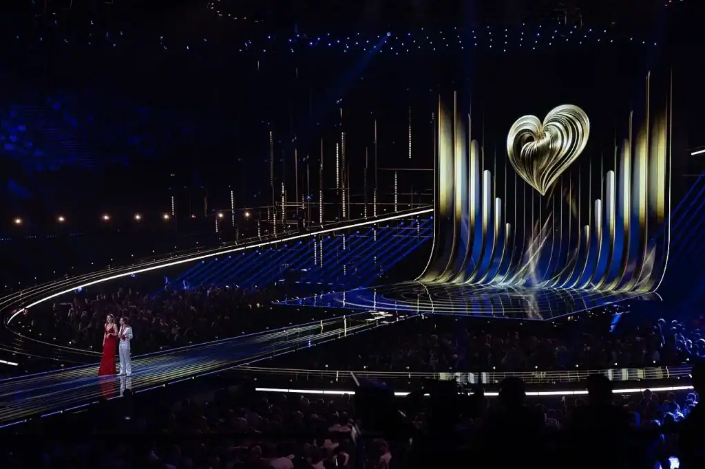 Euroviisulava, jossa sydämen muotoinen Euroviisujen logo ja kaksi juontajaa.