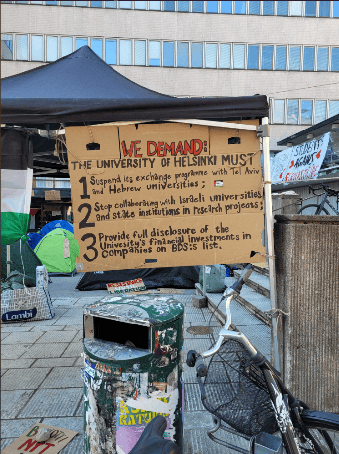 A hand written sign with the text: We demand the university of Helsinki must 1. Suspend its exchange programme with Tel Aviv and Hebrew Universities; 2. Stop collaborating with Israeli universities and the state institutions in research projects; 3. Provide full disclosure of the university's financial investments in companies on BDS's list.