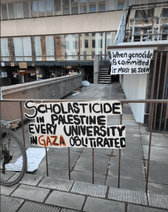 A hand written sign: Scholasticide in Palestine, every university in Gaza oblitirated.