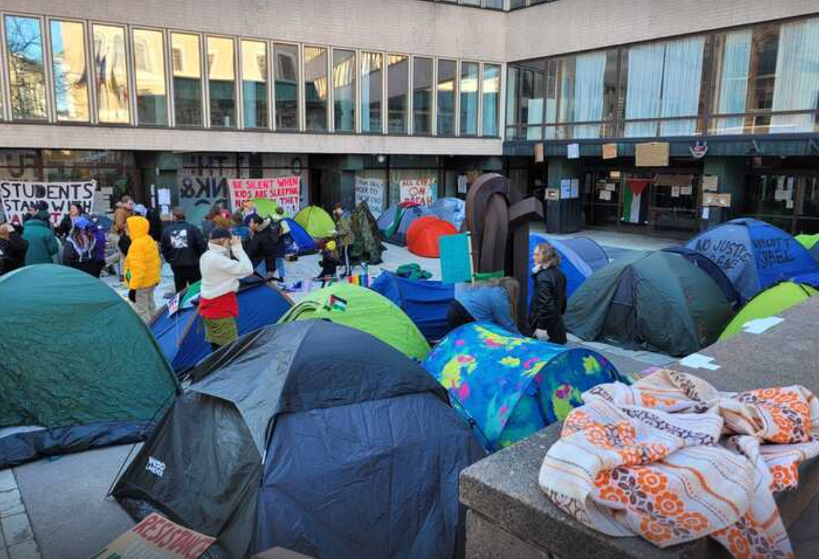 Colourful tents, students and a scarf in front of Porthania building.